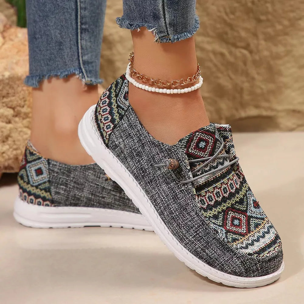 Gray Aztec print slip on sneakers with a white sole, side view on foot