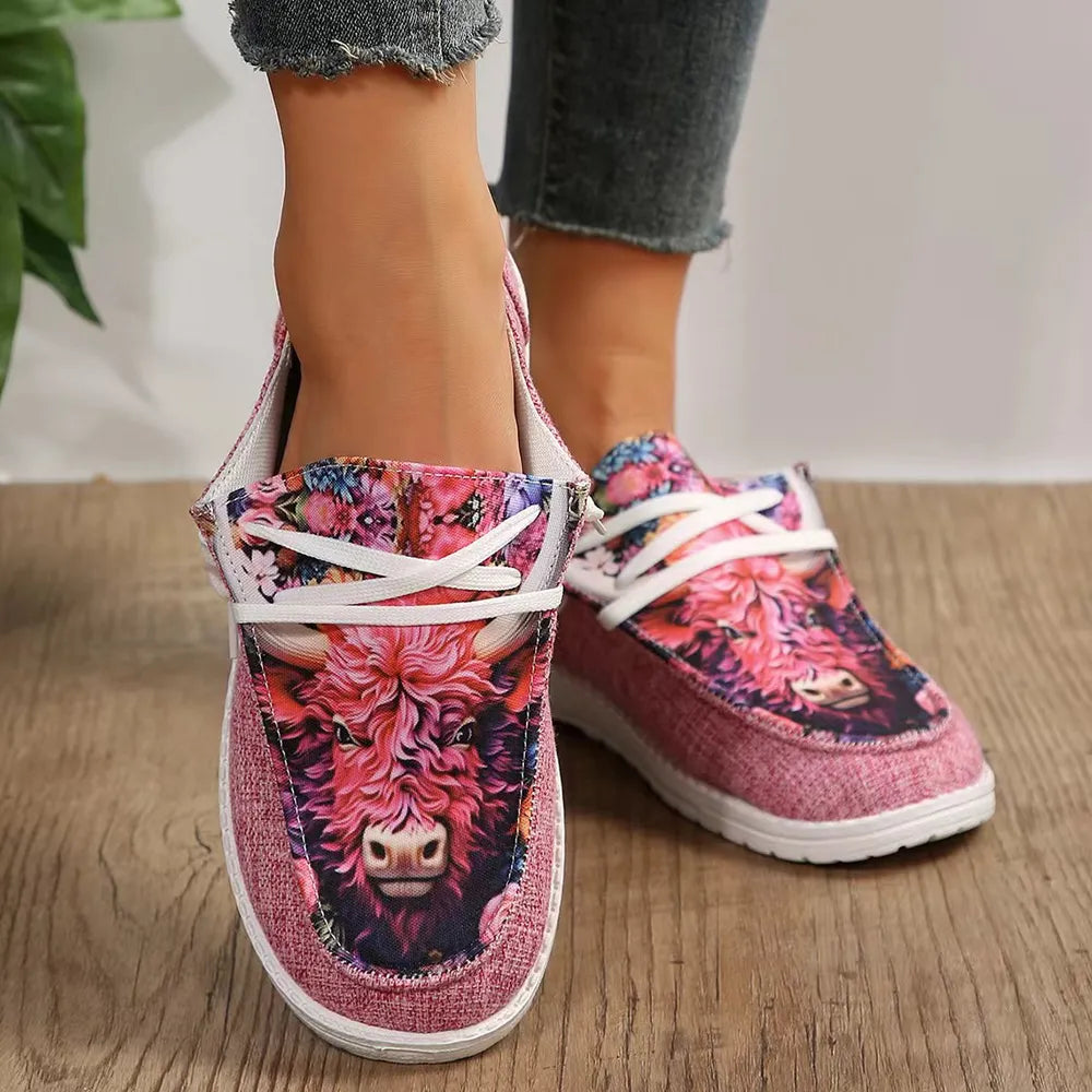 Pink bull print slip on sneakers with floral pattern, front view on wood