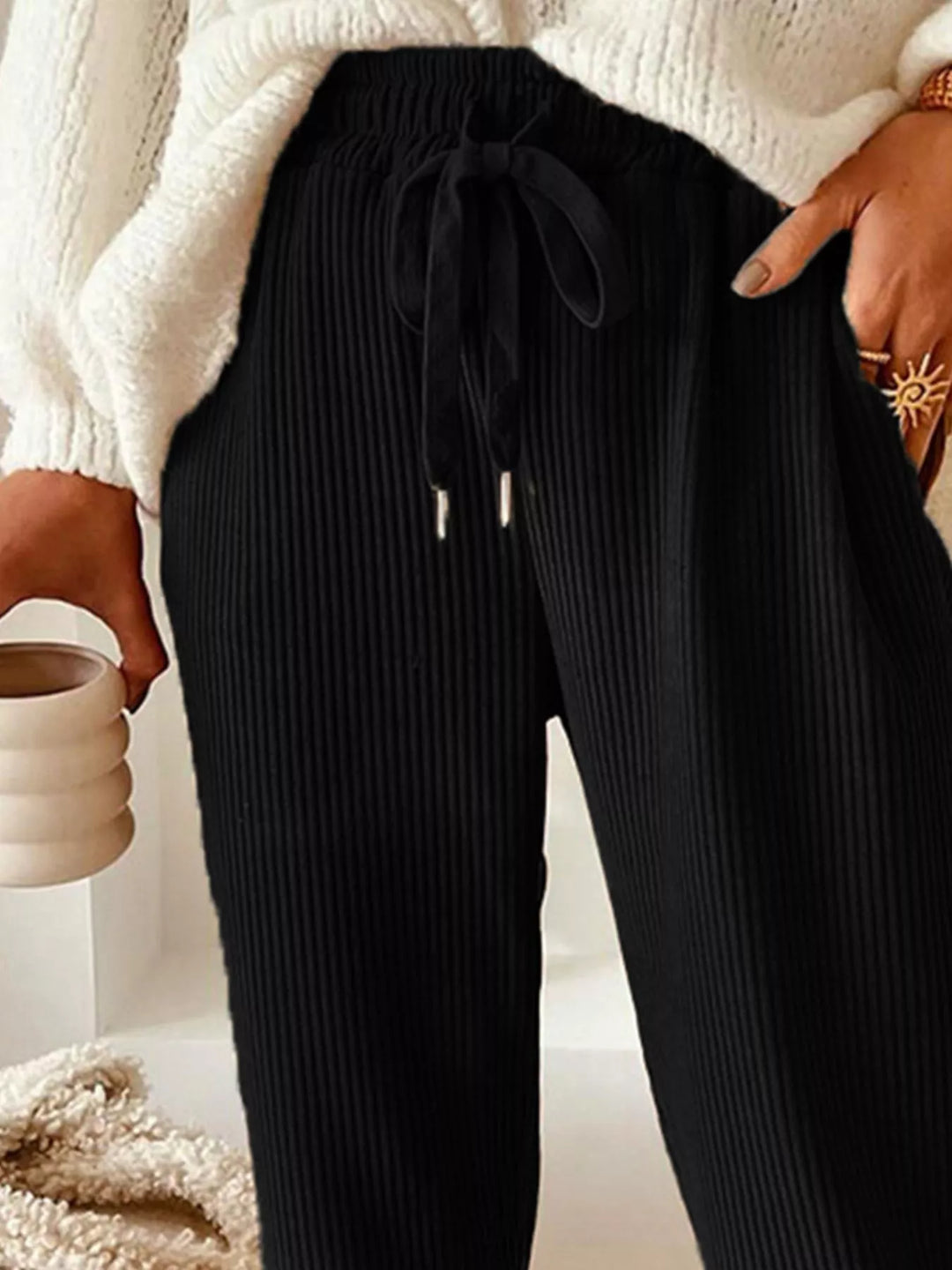 Close-up of the black ribbed drawstring waist with hand in pocket
