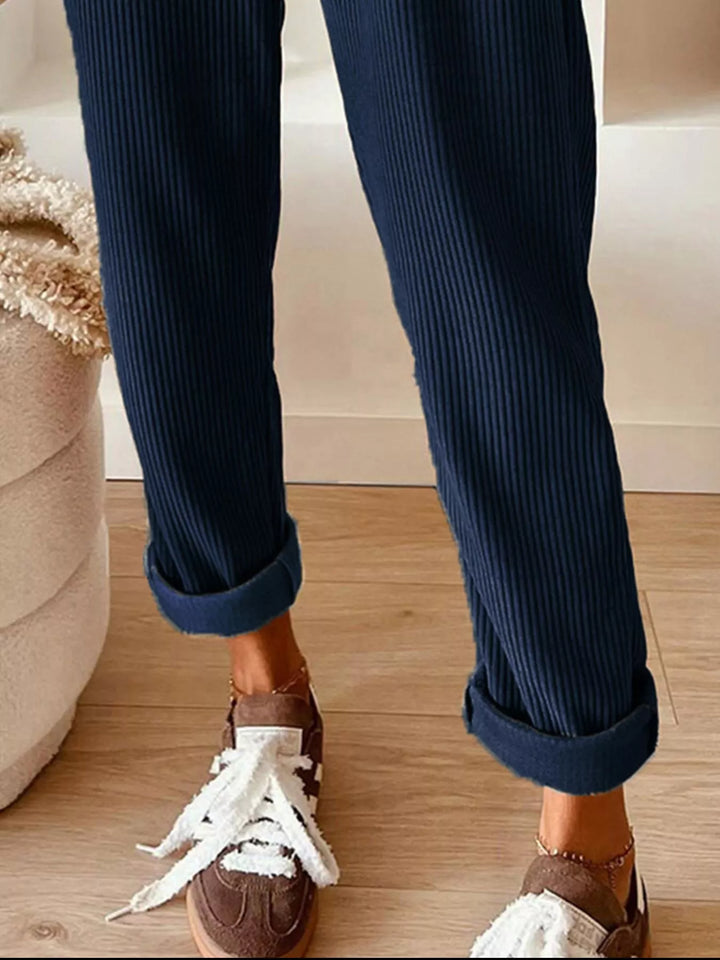 Navy straight leg pants with cuffed ankle above white sneakers