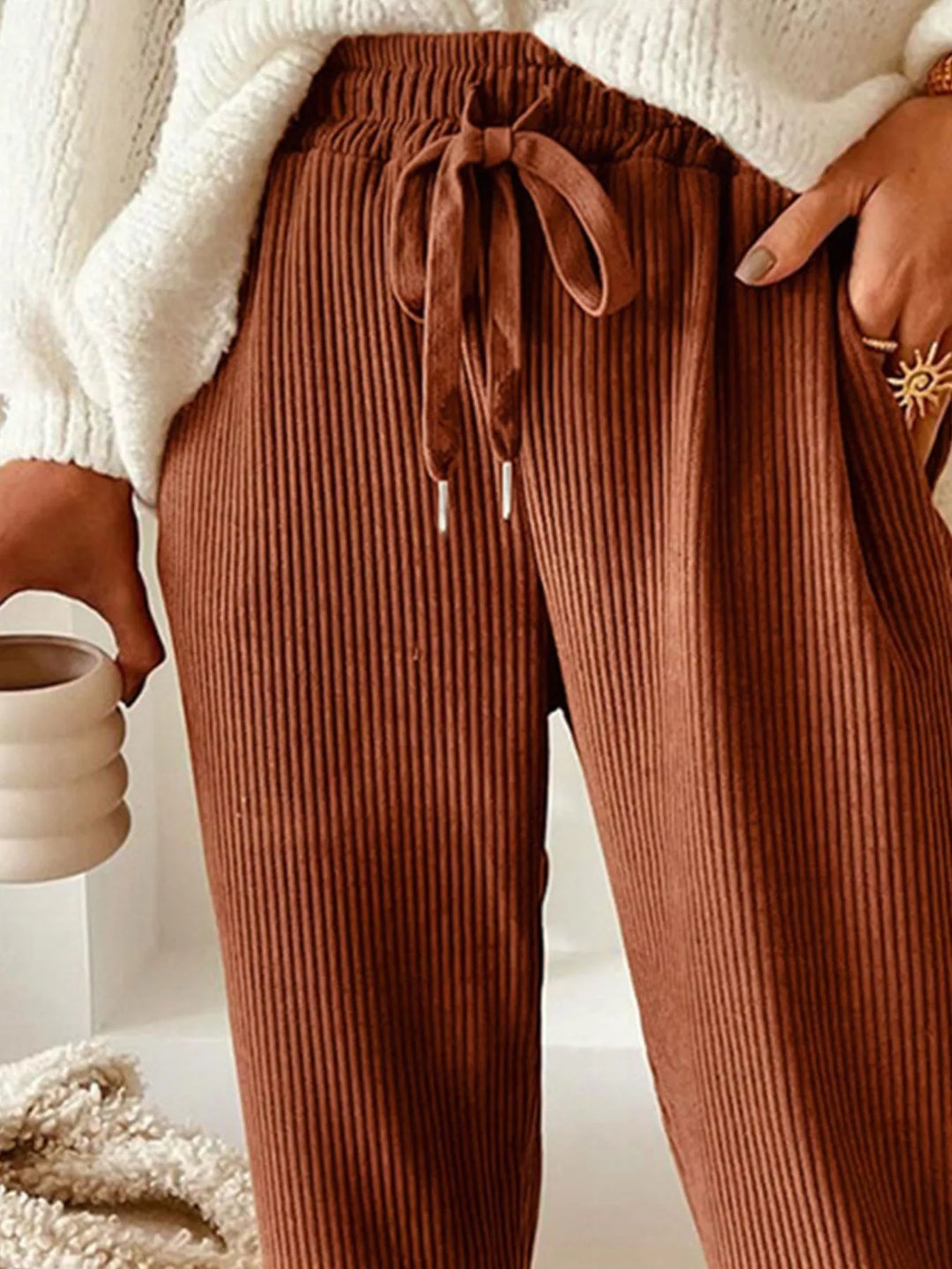 Close-up of the rust ribbed pants drawstring waist and side pocket