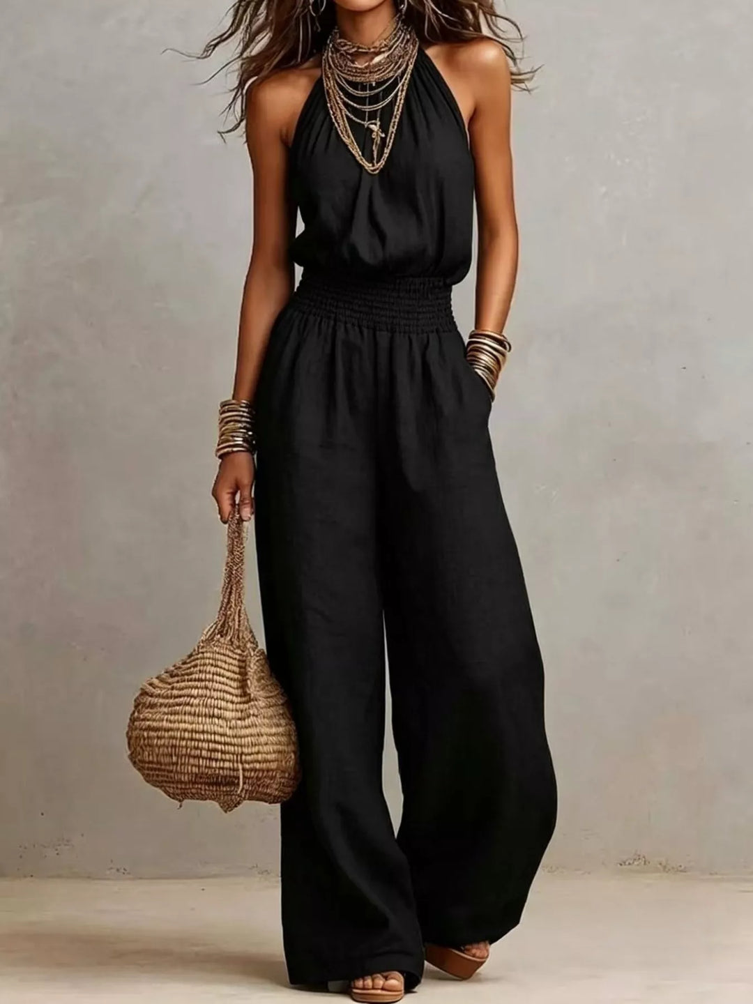 Black halter neck summer jumpsuit with wide leg and a woven bag