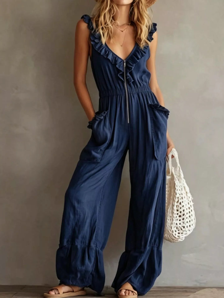 Navy sleeveless wide leg jumpsuit with ruffle V neck, front view with a mesh bag