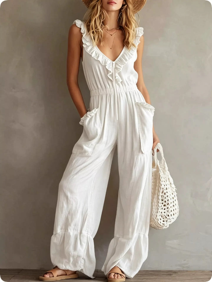 White sleeveless wide leg jumpsuit with ruffle neckline, standing pose