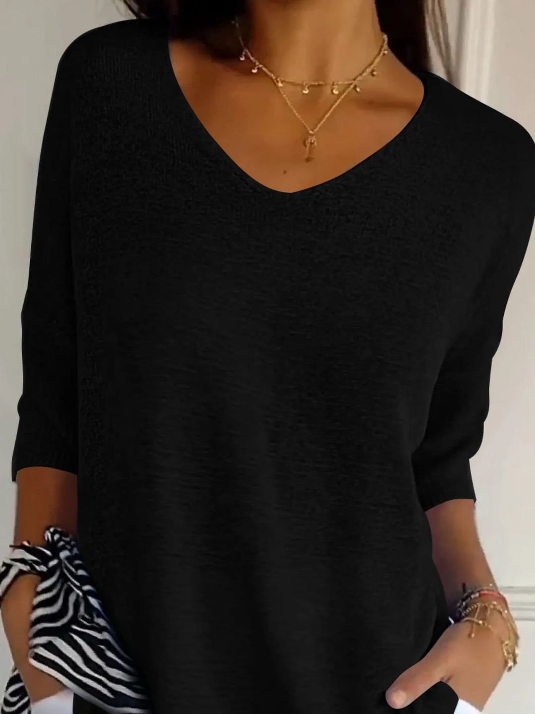 Black V neck sweater close-up of the neckline and layered necklaces