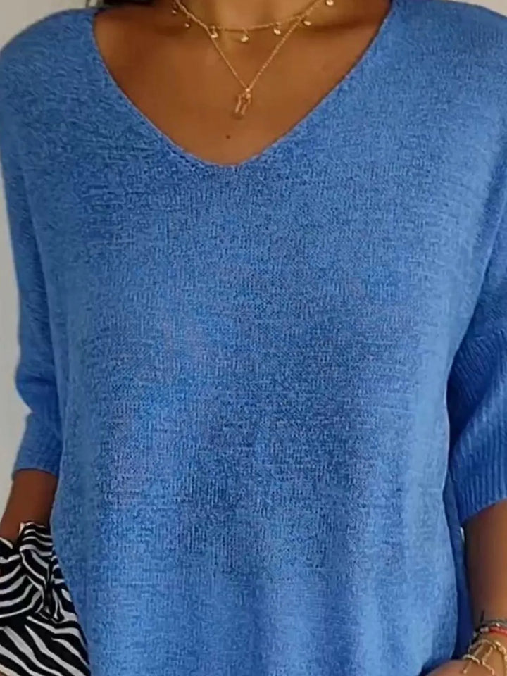Blue sweater V neckline close-up with a zebra print scarf at the side