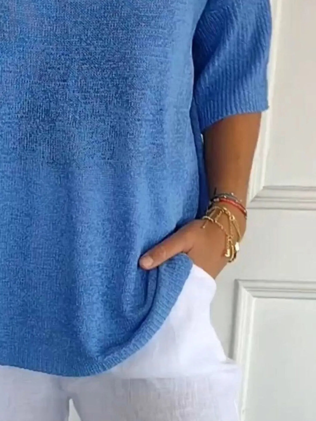 Blue lightweight sweater close-up of the ribbed sleeve and hand in pocket
