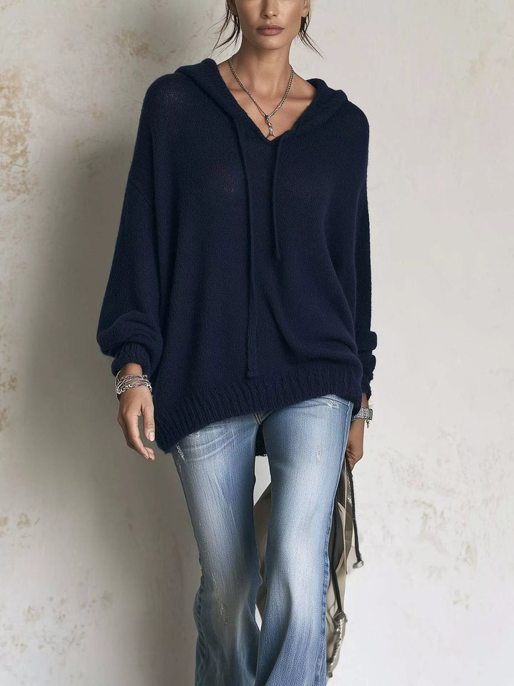 Navy oversized hooded knit sweater worn with flared jeans