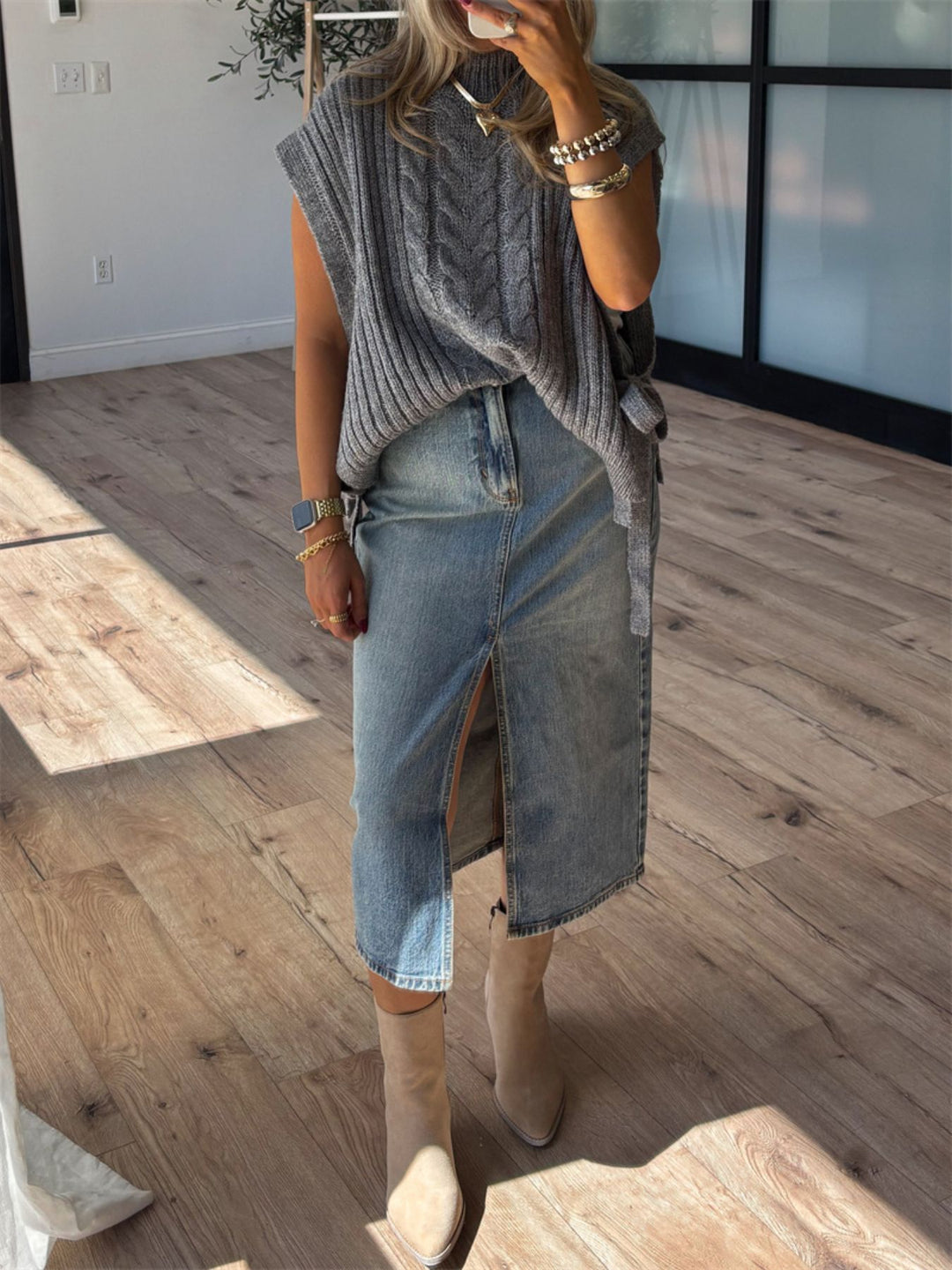 Gray cable knit vest with a denim midi skirt and boots, full length view