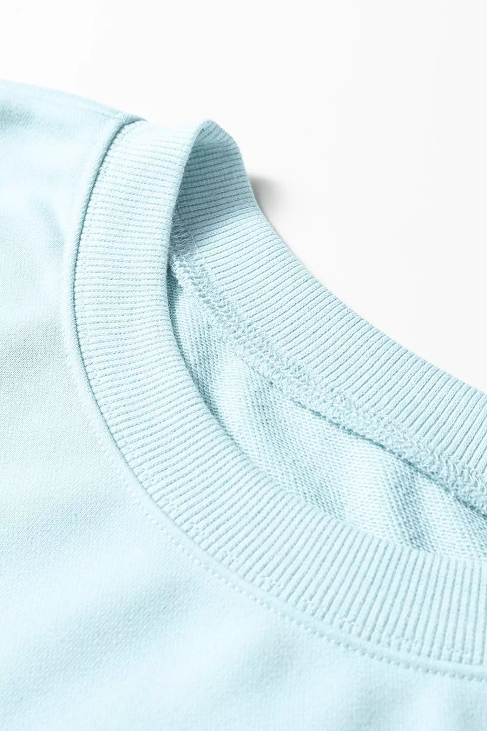 Close-up of the ribbed crew neckline on the pastel blue pullover