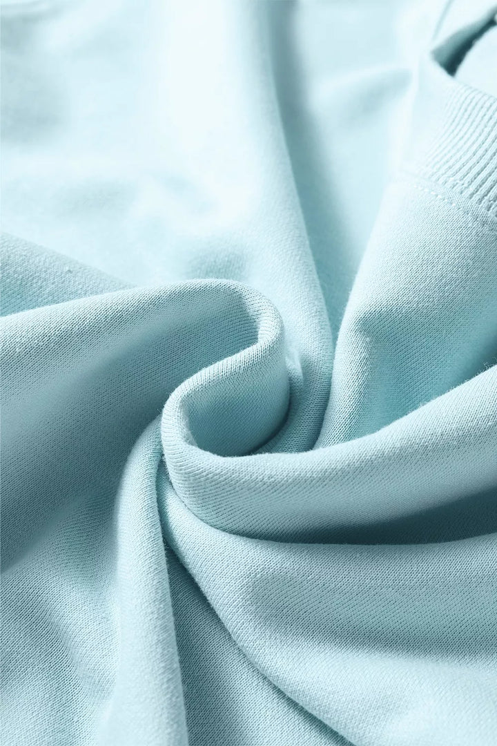 Soft folds of pastel blue fabric from the sweatsuit in close-up