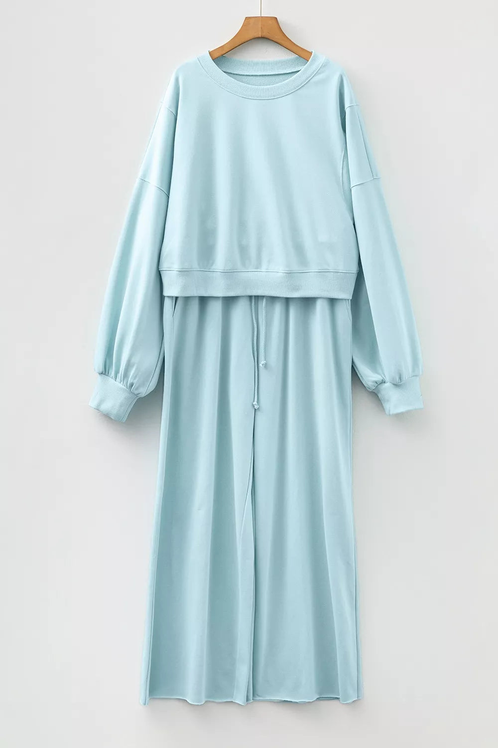 Pastel blue sweatsuit pullover and pants hung together on a hanger, front