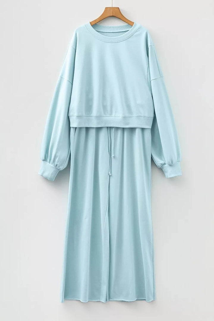 Pastel blue sweatsuit pullover and pants hung together on a hanger, front