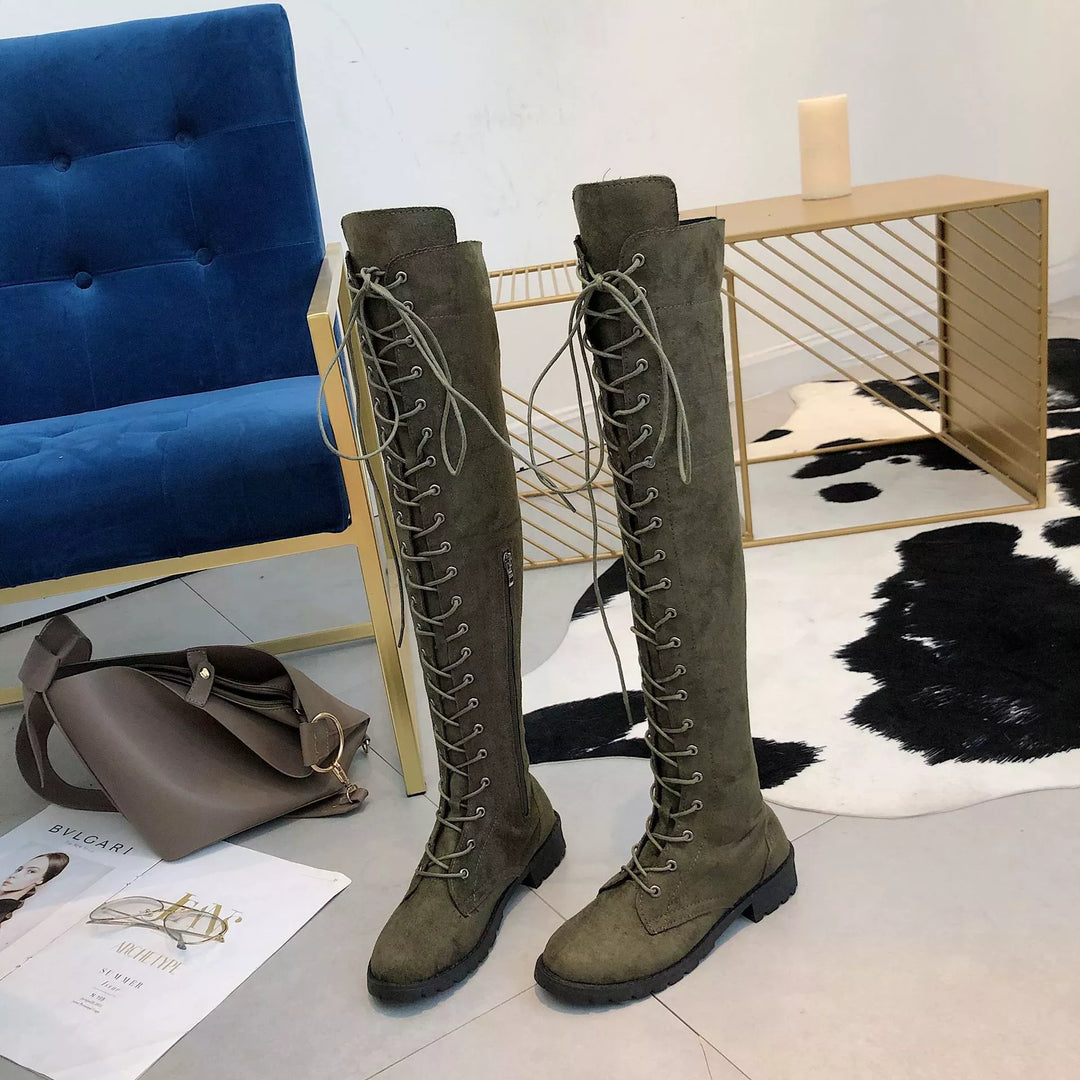 Pair of olive over the knee lace up boots next to a chair