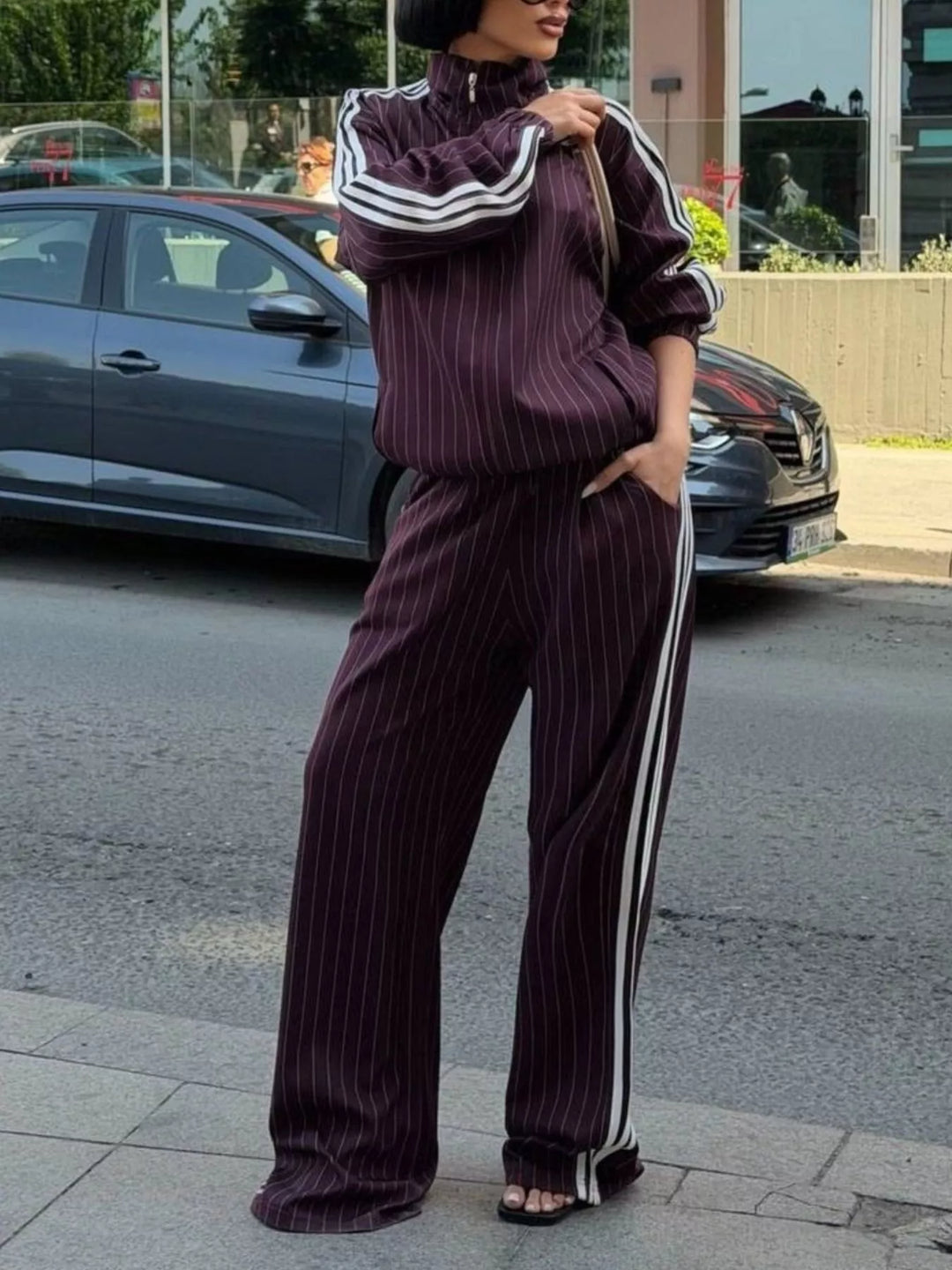 Burgundy pinstripe track jacket with high collar, hand in pocket pose