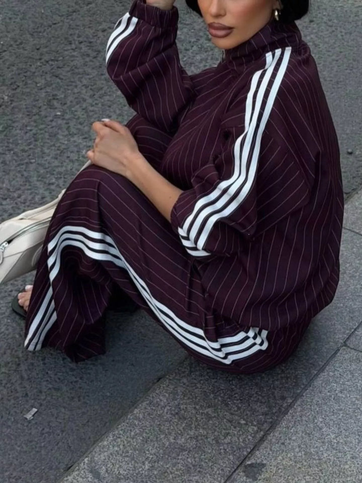Burgundy pinstripe tracksuit set worn while crouching on the pavement