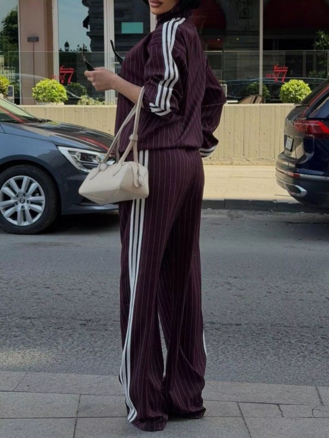 Burgundy pinstripe tracksuit styled with a cream shoulder bag