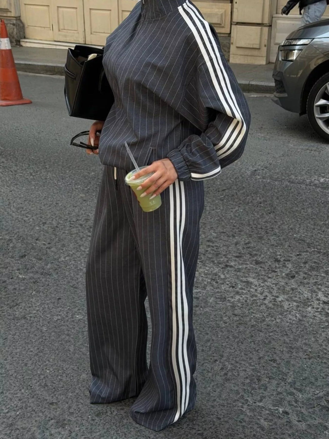 Gray pinstripe zip jacket and wide leg pants, carrying an iced drink and bag
