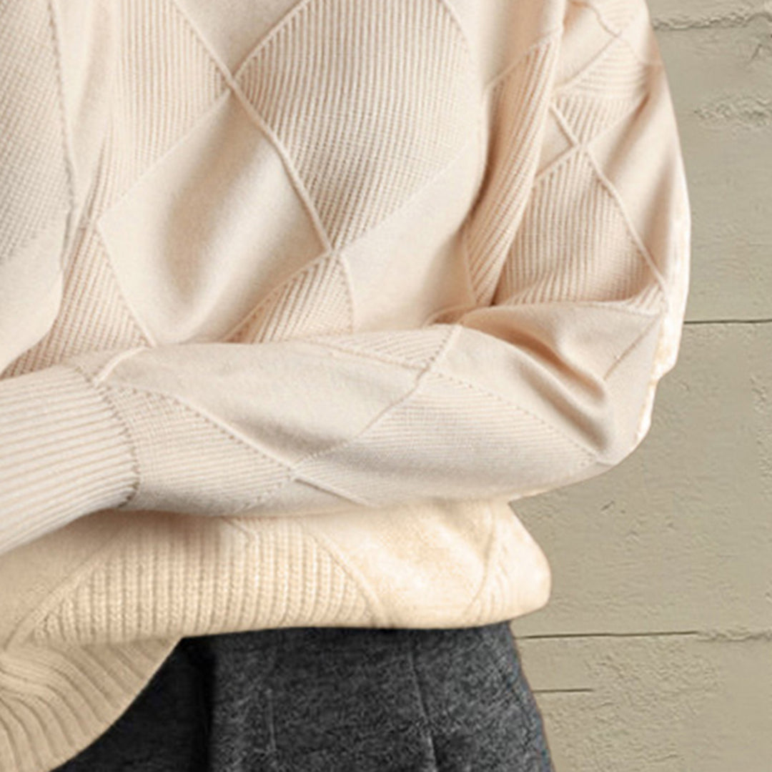 Close-up of the ivory geometric diamond knit sleeve and ribbed cuff