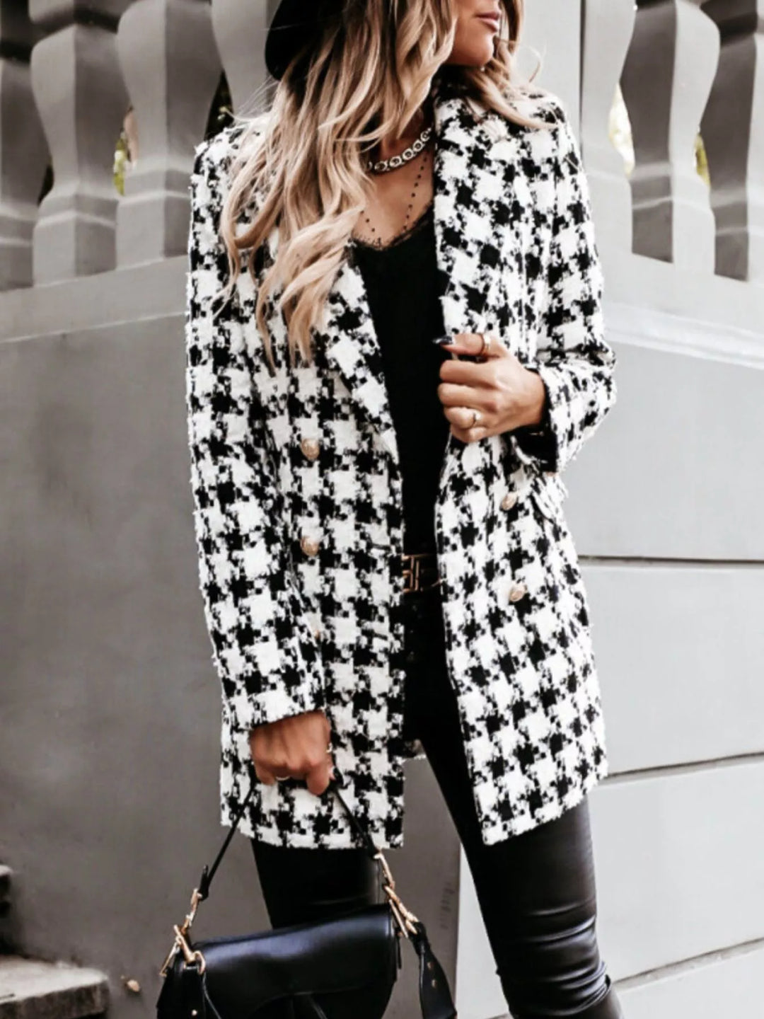 Houndstooth longline blazer in a three quarter turn with hand at the lapel
