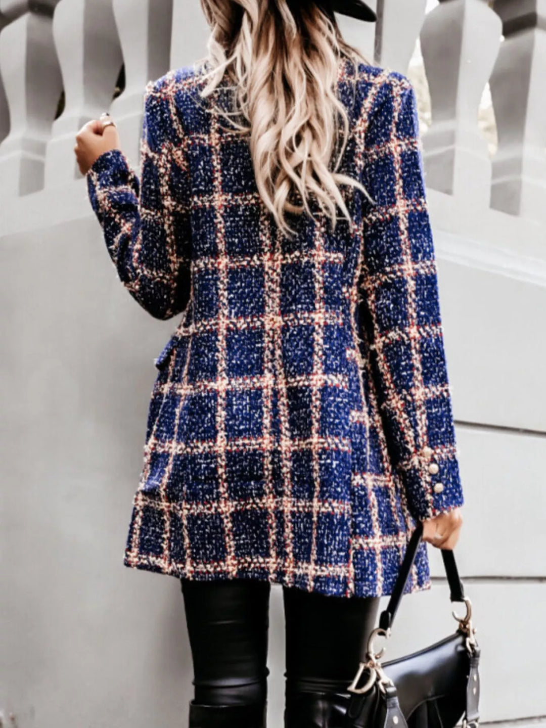 Navy plaid double breasted coat from a side angle holding a bag