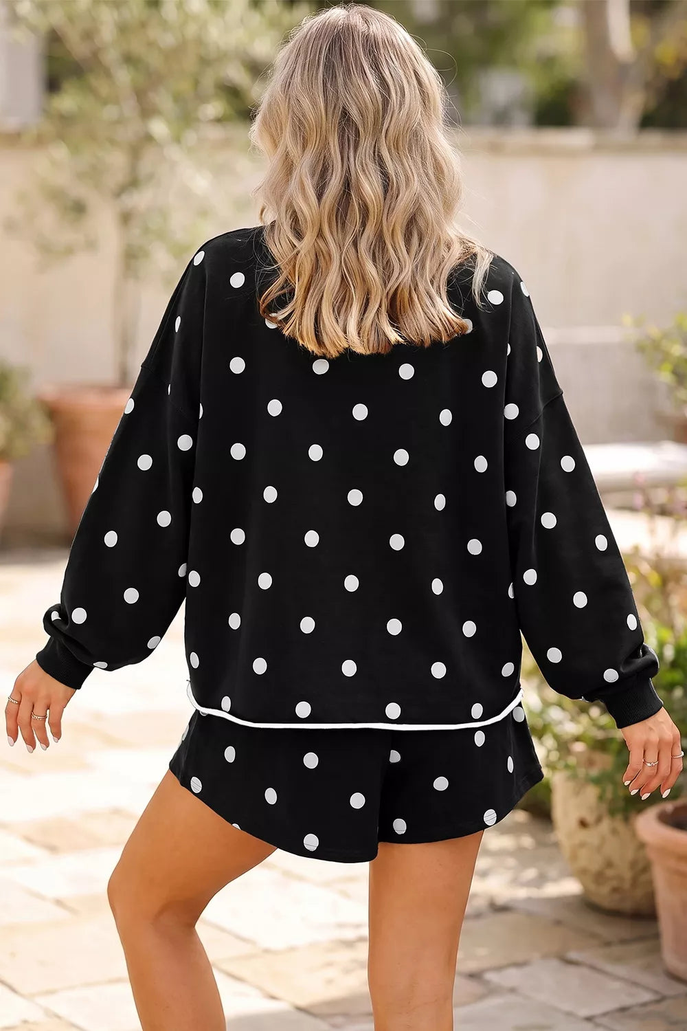 Back view of the black polka dot sweatshirt and ruffle skort outdoors