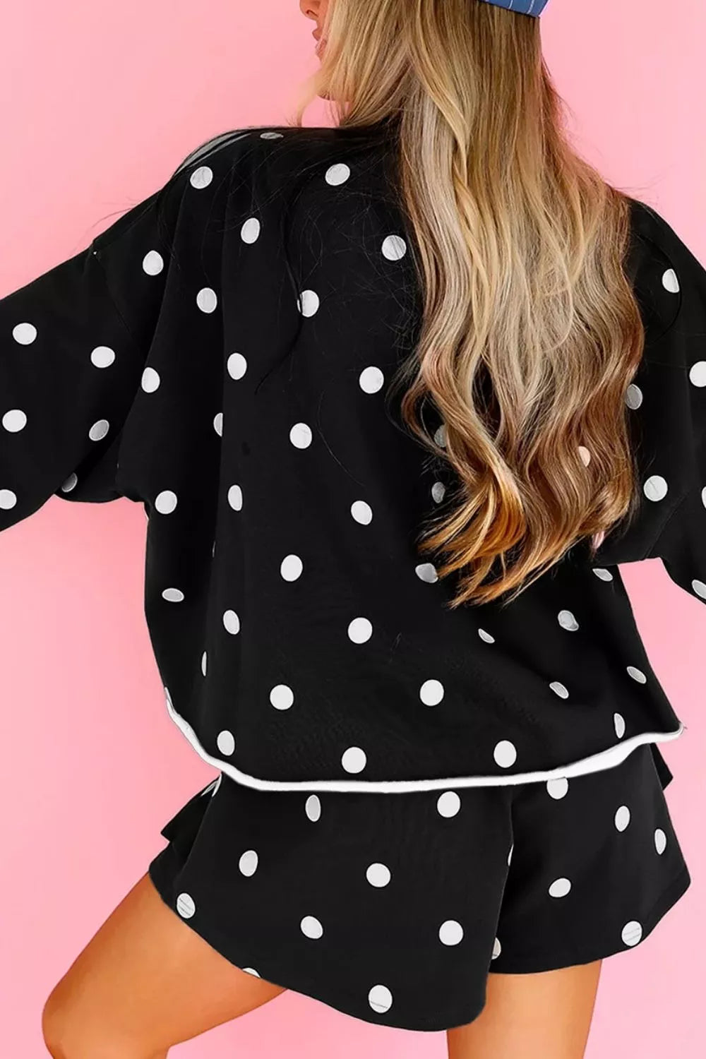 Side and back angle of the black polka dot sweatshirt with ruffle skort hem