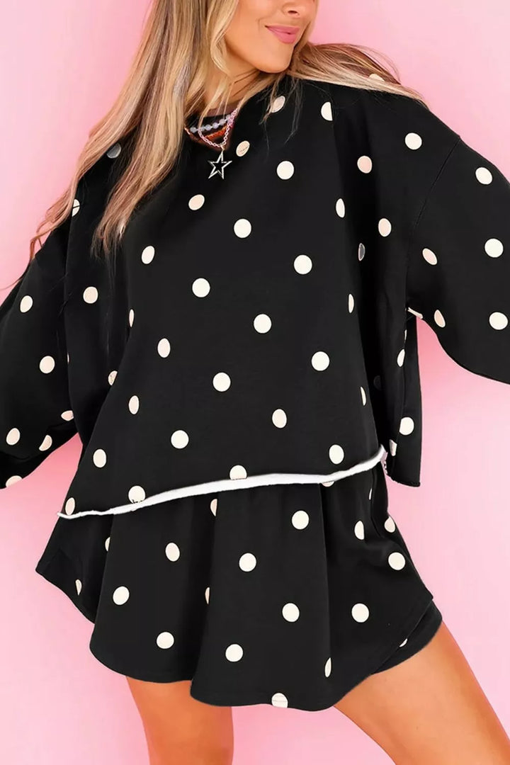 Black polka dot sweatshirt and skort set against a pink backdrop, front angle