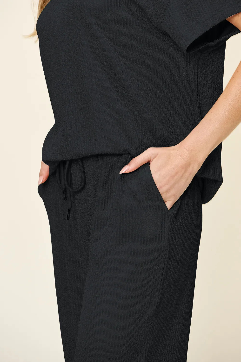Close-up of the black drawstring waist and hand in pocket
