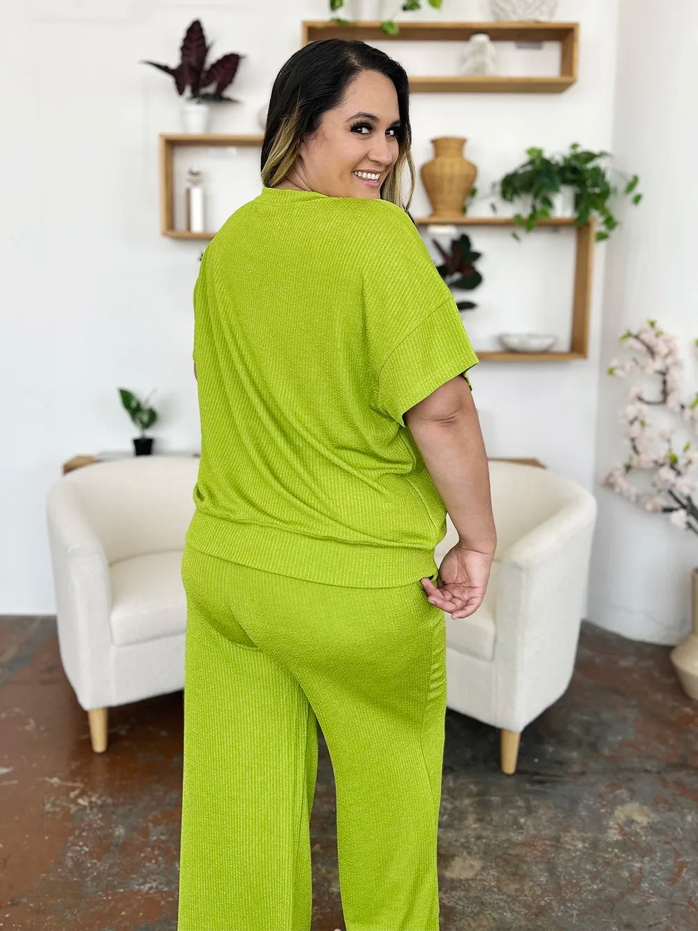 Back view of the lime green short sleeve top on a curvy model