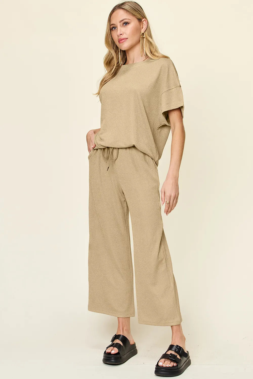 Tan short sleeve top and cropped wide pants, side angle with hand in pocket
