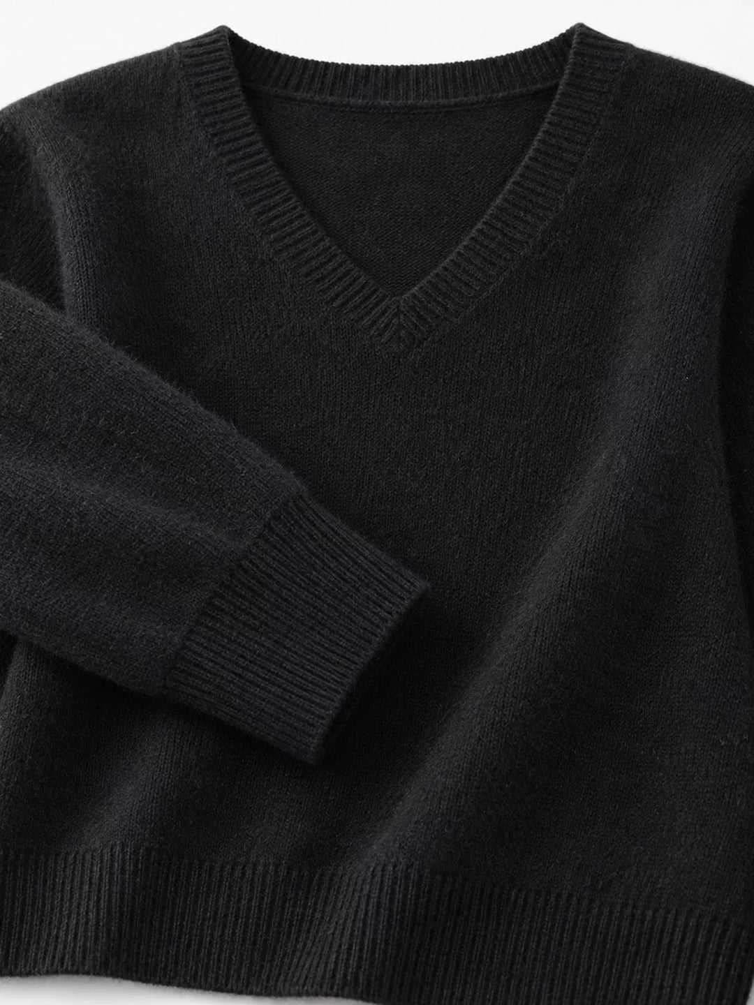 Close-up details of the black sweater neckline, ribbed cuff and hem