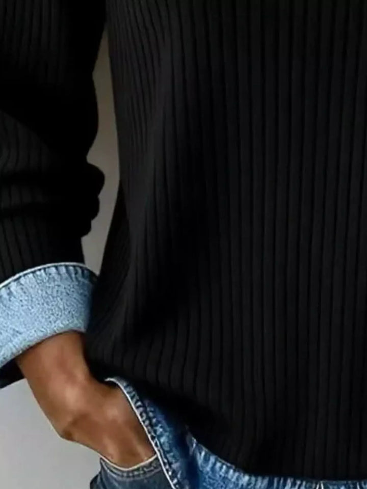Close-up of the black ribbed knit sweater cuff and layered hem detail