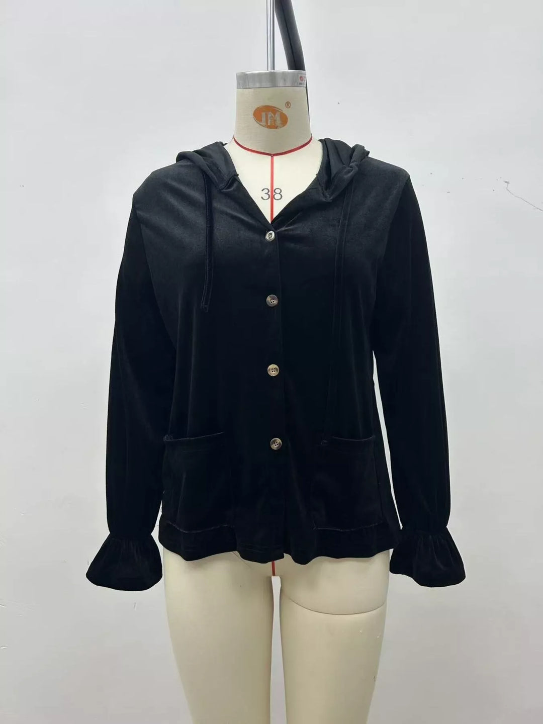 Front view of the black hooded velvet jacket with patch pockets and ruffle cuffs
