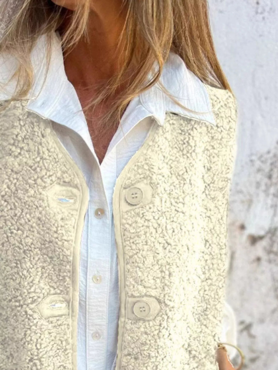 Close-up of the cream textured vest front and button closure