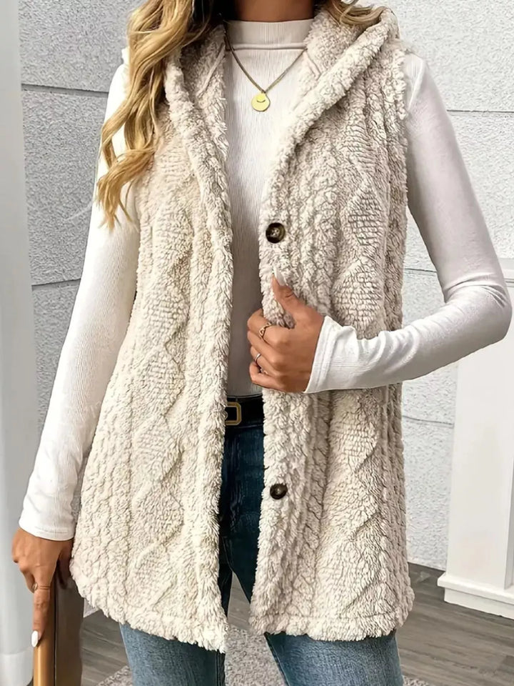 Women's vest in beige, hooded fuzzy cable knit button front, worn over a white top