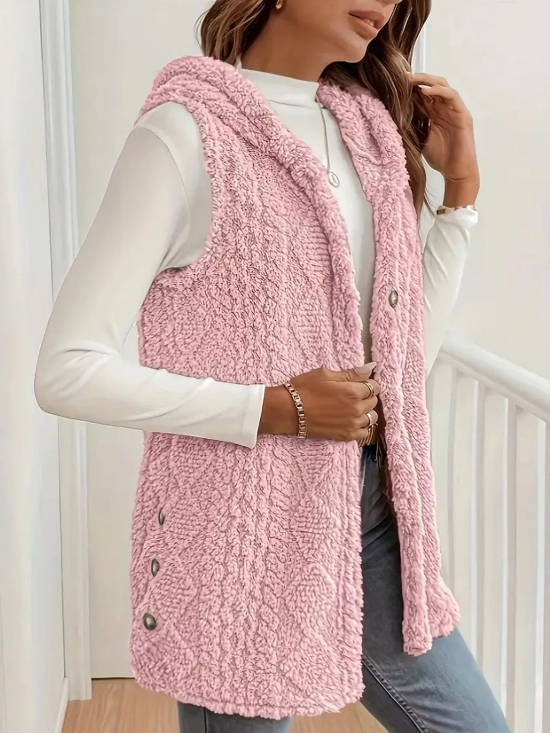 Blush pink cable knit vest from the side with buttons along the hem
