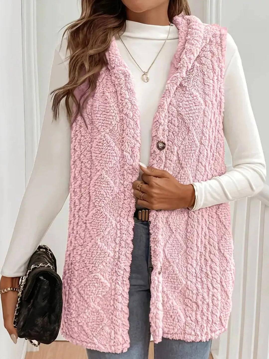 Blush pink hooded vest styled with a black quilted bag and jeans