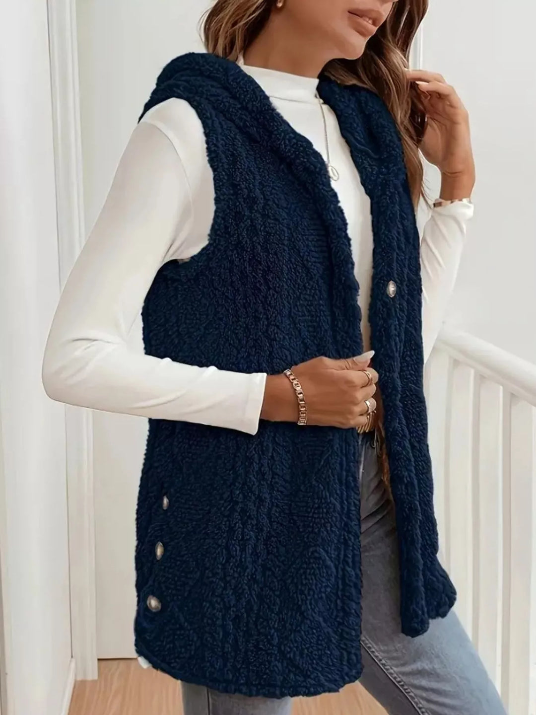 Navy cable knit vest side view with side button trim and hood down
