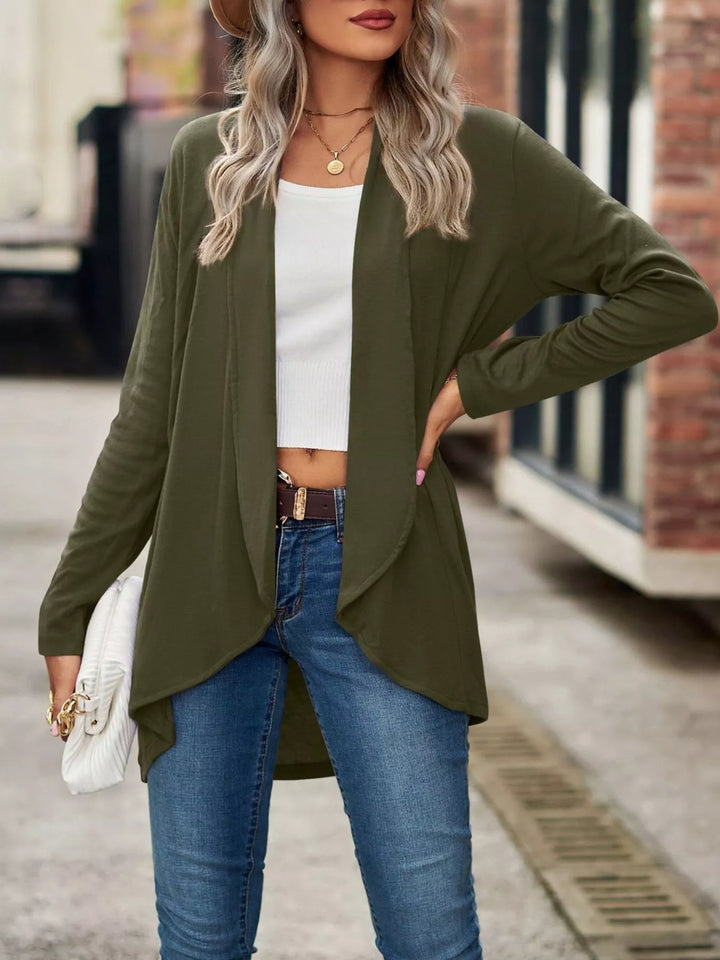 Olive green cardigan in a hand on hip pose, worn with blue jeans
