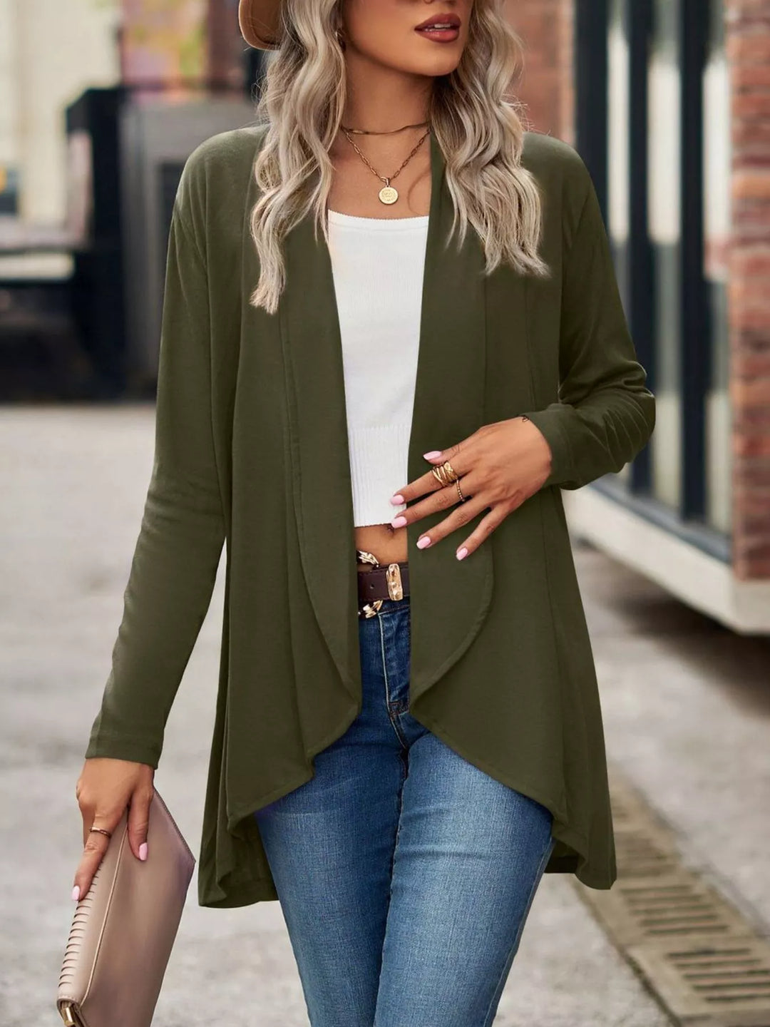 Olive green long cardigan with high low hem, holding a pink clutch