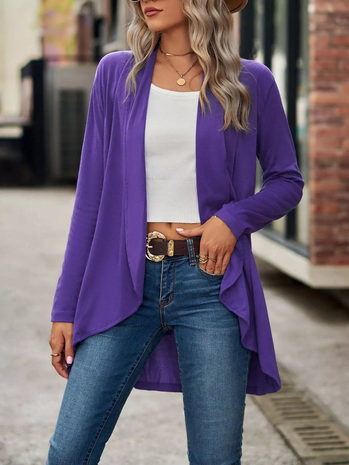 Purple open front cardigan with high low hem, standing pose with jeans and belt