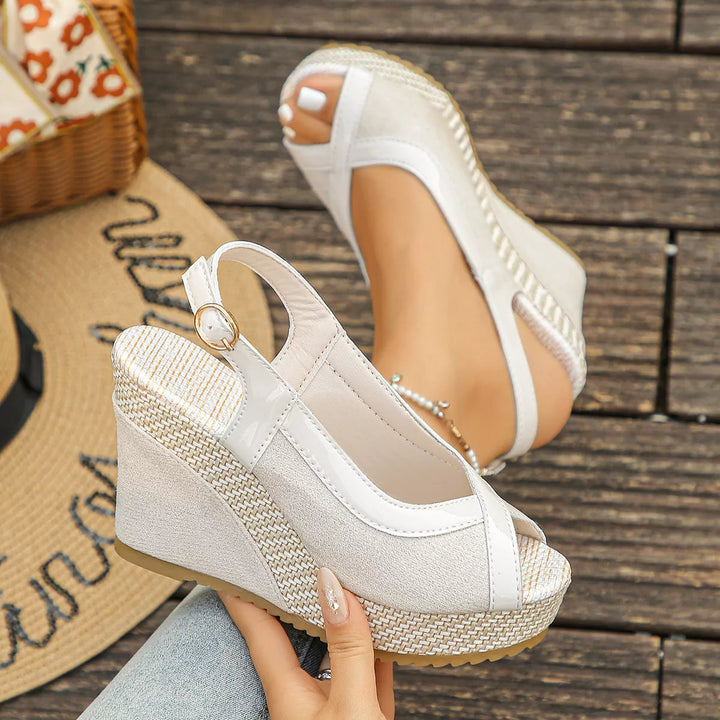 Off white platform wedge sandals held in hand showing the buckle strap