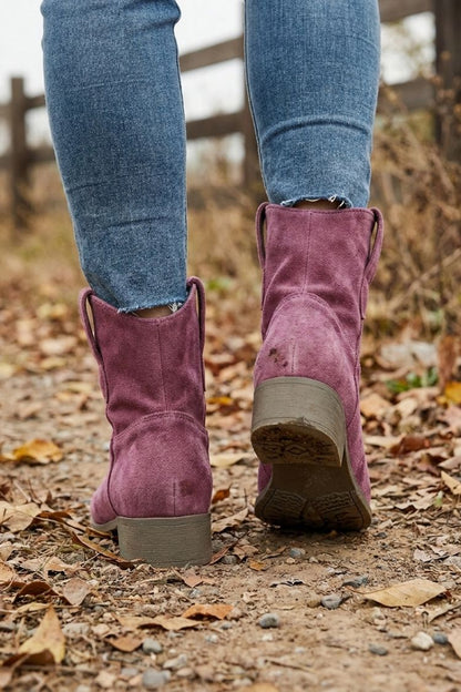 Burgundy western booties worn on a fall walk, rear view