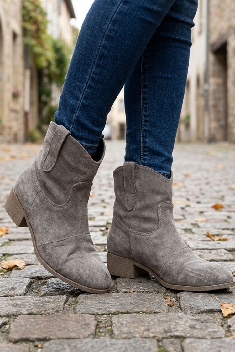 Grey western ankle boots worn with jeans on a city street