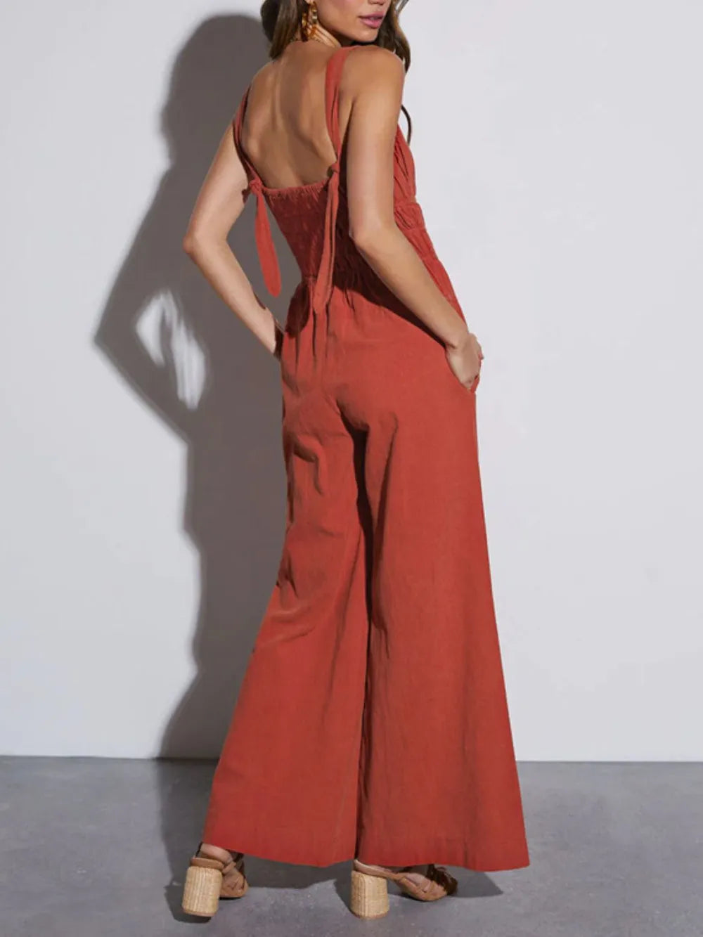 Back view of rust wide leg jumpsuit with tie back and thin straps