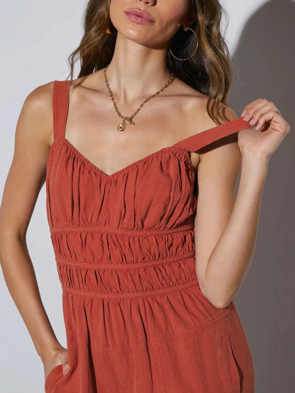 Close-up of rust jumpsuit ruched smocked bodice and adjustable strap