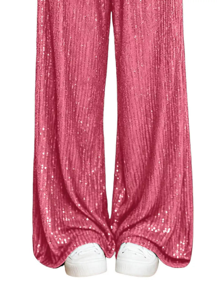 Hot pink sequin wide leg pants hem over white sneakers