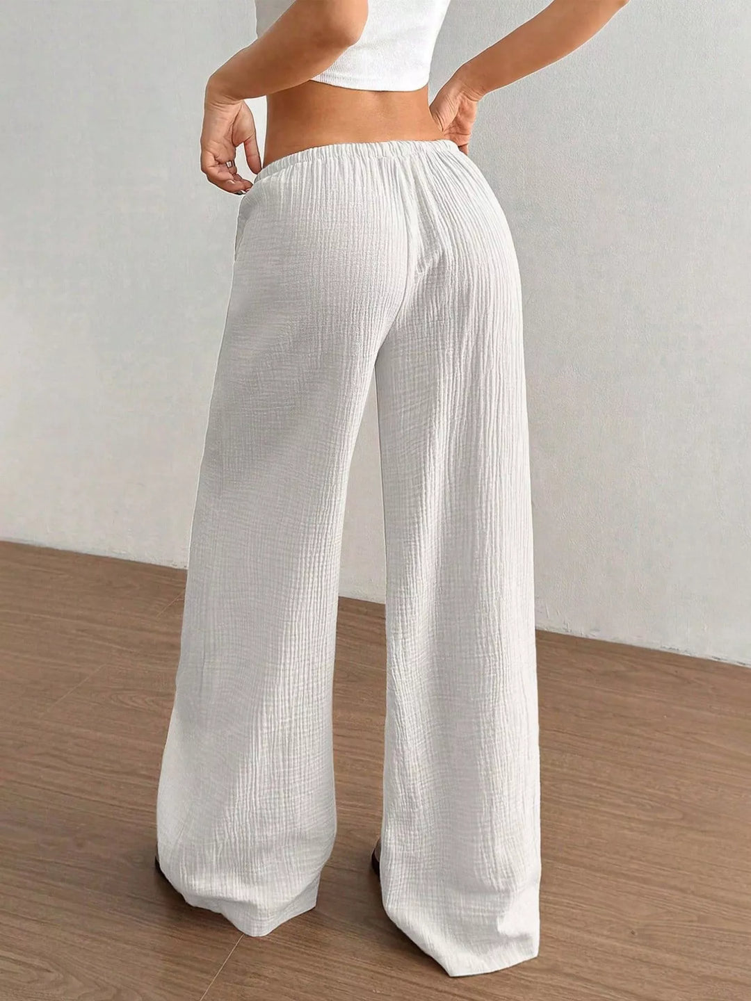 White wide leg pants from behind with hands on hips
