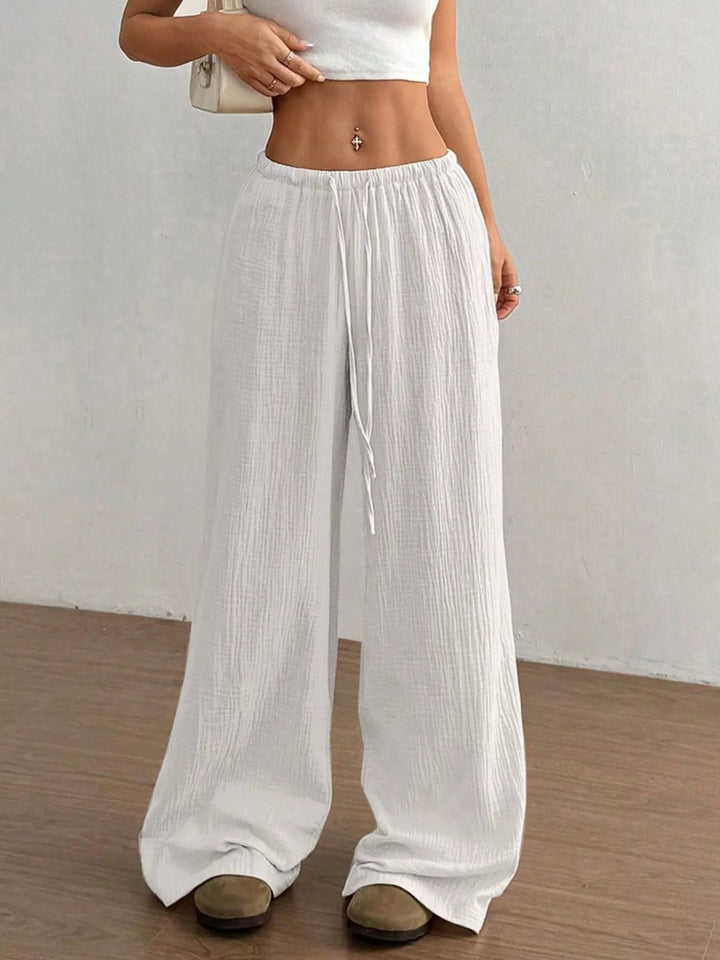 White crinkled wide leg pants worn with a cropped white top, front angle
